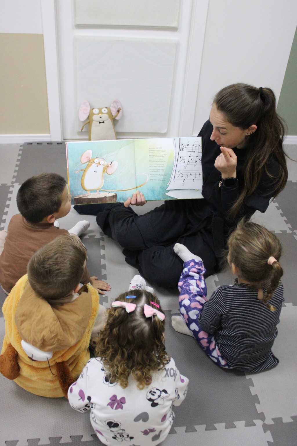 Professora apresenta um livro ilustrado às crianças sentadas em roda